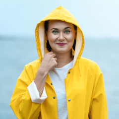 Nainen meren rannalla keltaisessa sadetakissa.