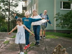 Isä, äiti, poika ja tyttö tasapainoilevat jonossa kalliolla.