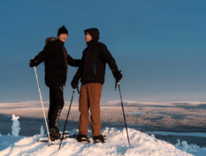 Two people on the top of a hill with skies.