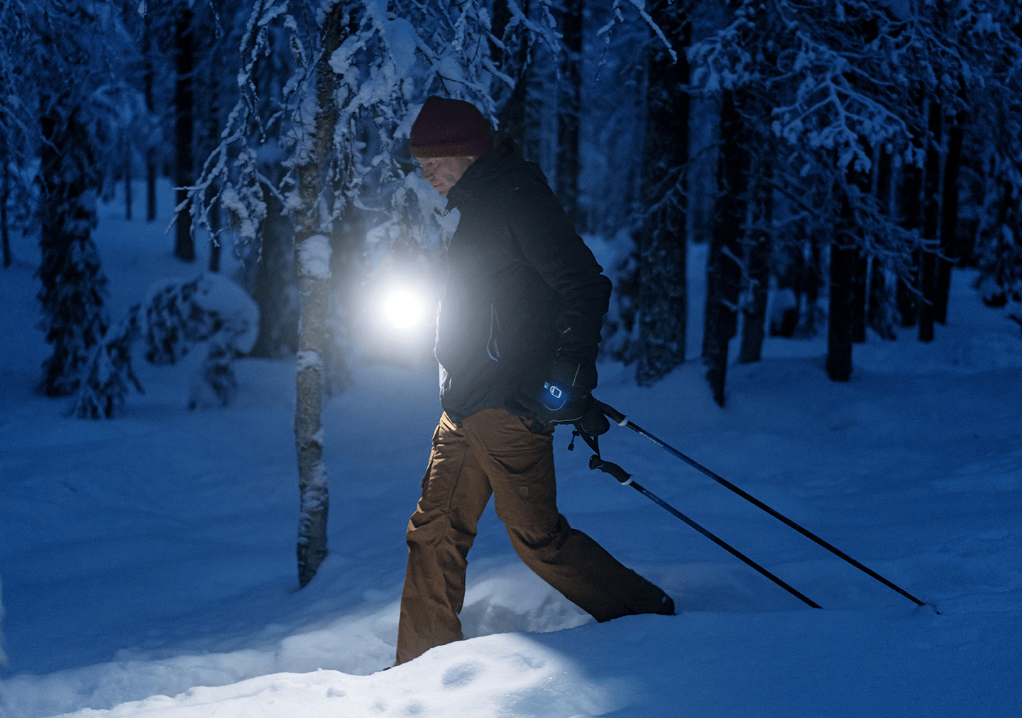 A person skiing in the dark with a lamp.