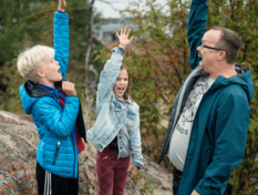 Family standing in a forest and raising their hands.