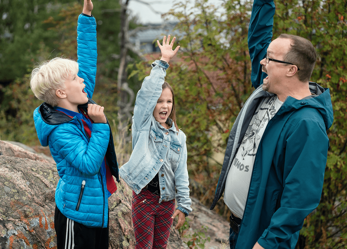 Family standing in a forest and raising their hands.