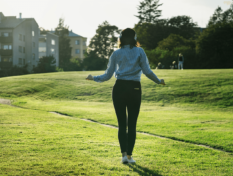 Young female student with headphones on outside