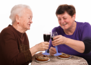 Kaksi iäkästä ihmistä skoolaa viinilaseilla.