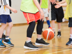 Nuoria pelaamassa koripalloa liikuntasalissa.