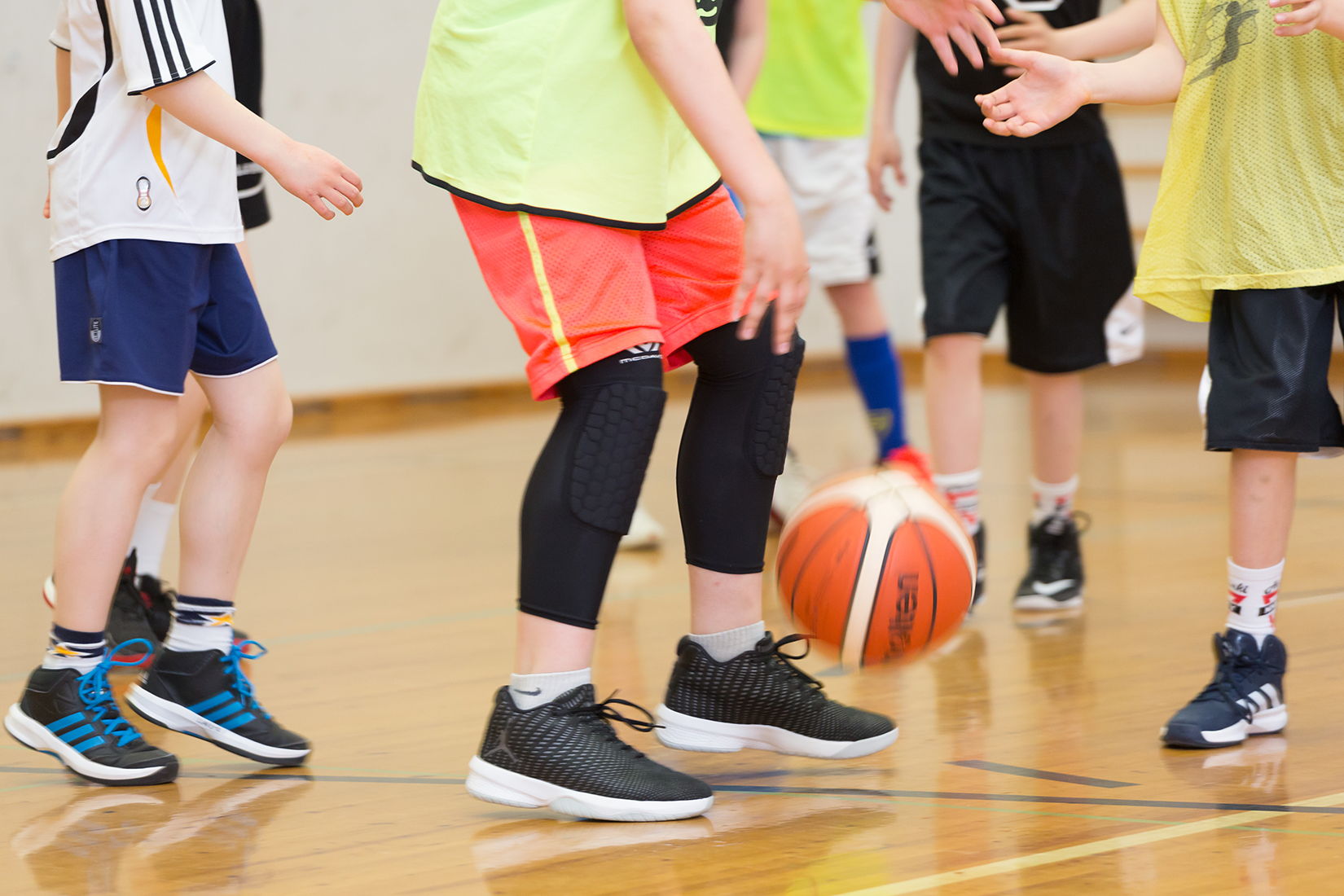 Nuoria pelaamassa koripalloa liikuntasalissa.