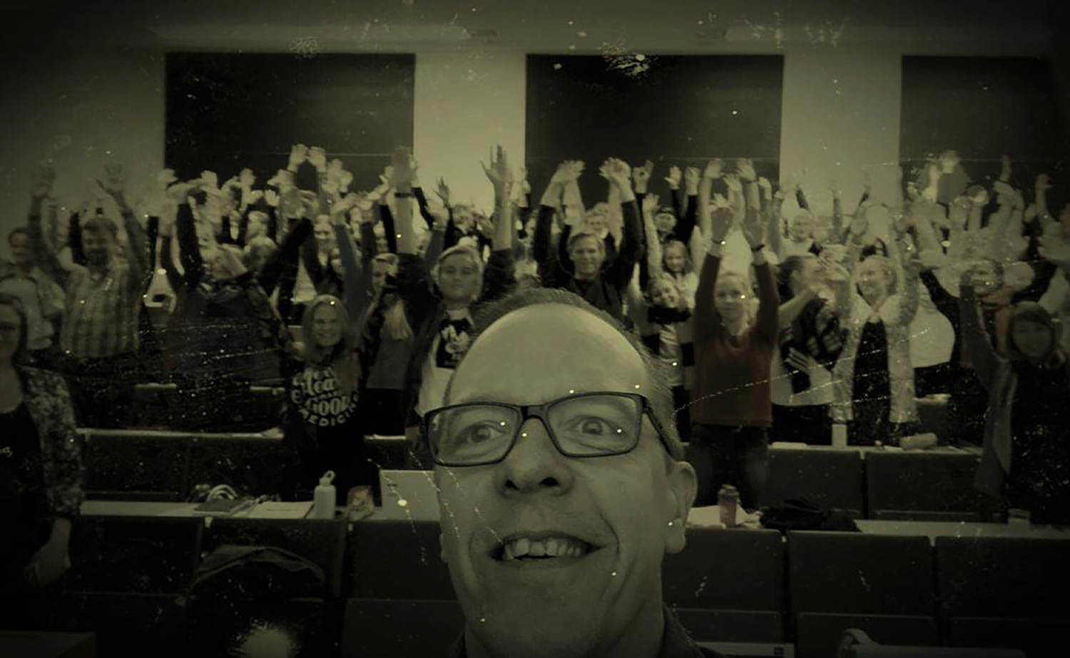 Selfie-kuva Kim Kannussaaresta ja luentosalillisesta opiskelijoita.