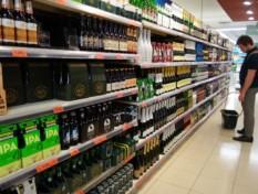 A person standing in front of alcohol products in a supermarket.