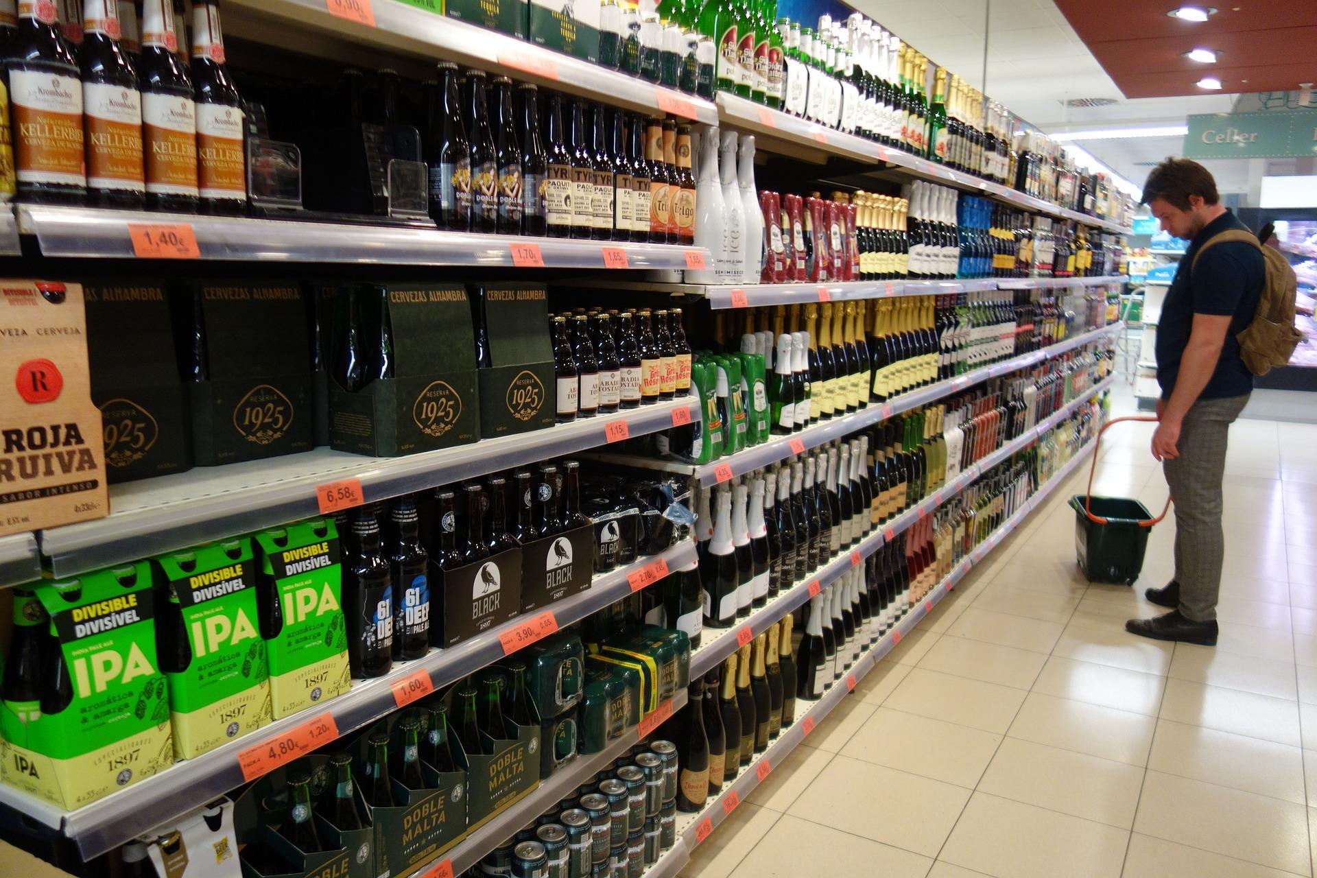 A person standing in front of alcohol products in a supermarket.