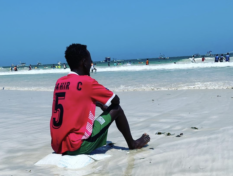 Nuori istuu rannalla Mogadishussa ja katsoo merta.
