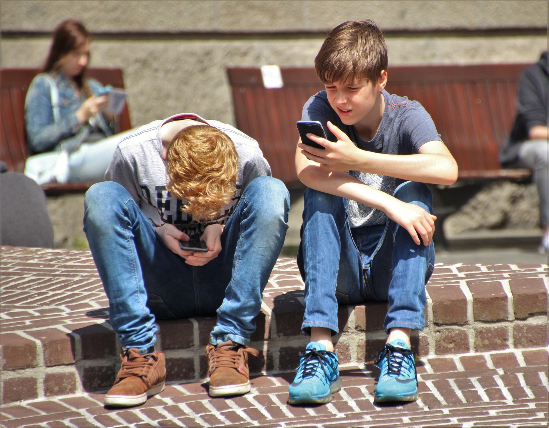 Nuoria istumassa rappusella kännyköiden kanssa.
