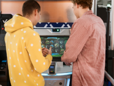 Kaksi nuorta pelaa rahapeliautomaatilla.