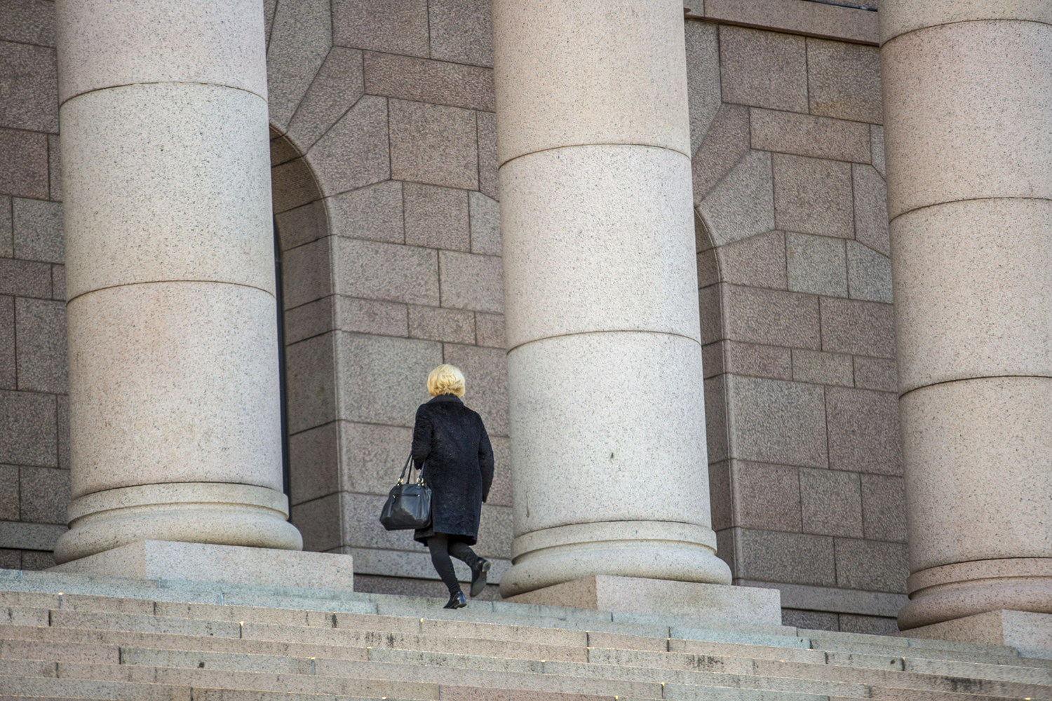 ihminen kävelee eduskunnan portaita ylöspäin.